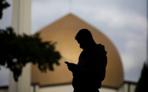 A member of the Muslim community uses his mobile phone out side the Al Noor mosque in Christchurch, New Zealand on March 15, 2020.