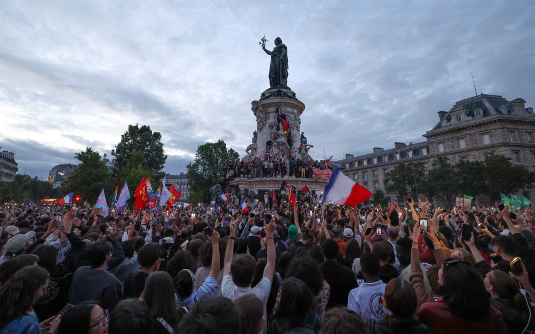 Participants wave French national tricolours during an election night rally following the first results of the second round of France's legislative election at Place de la Republique in Paris on July 7, 2024. A loose alliance of French left-wing parties thrown together for snap elections was on course to become the biggest parliamentary bloc and beat the far right, according to shock projected results.