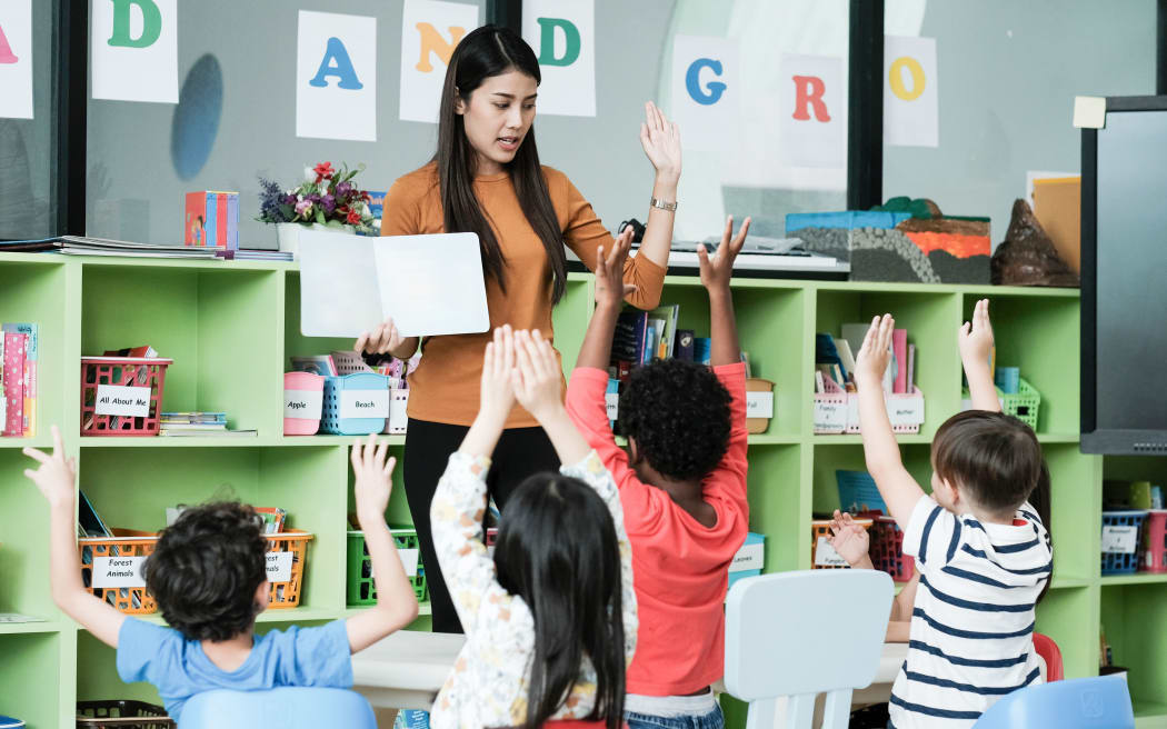 Young asian woman teacher teaching kids in kindergarten classroom, preschool education concept
