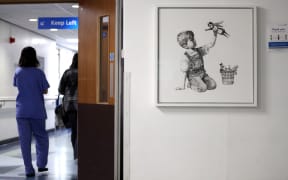 A person walks past the new artwork painted by Banksy during lockdown, entitled 'Game Changer', which has gone on display to staff and patients on Level C of Southampton General Hospital. (Photo by Andrew Matthews/PA Images via Getty Images)