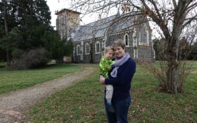 Cindy Driscoll and four-year-old Toby in from of the damaged St John's Church in Hororata.