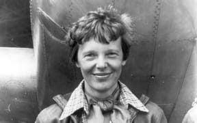 Amelia Earhart standing under the nose of her Lockheed Mode 10-E Electra
