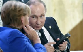 Russian President Vladimir Putin speaks with German Chancellor Angela Merkel during the first day of the COP21 climate change meeting in Paris.