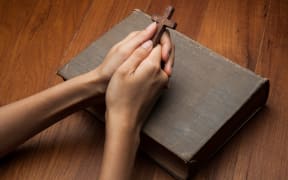 Hands folded in prayer over Holy Bible