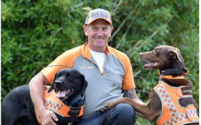 LandSAR dog handler Barry Dougherty plays with his two LandSAR area search dogs, black Labrador Jeffrey and kelpie Red, in Sidey Park yesterday. PHOTOS: PETER MCINTOSH