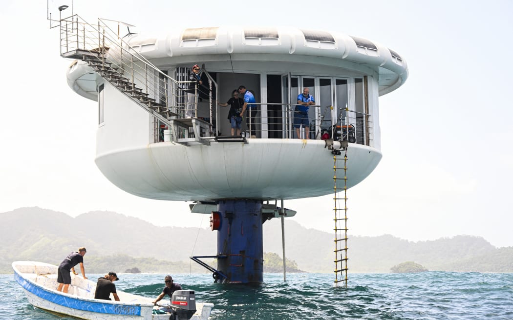 German aerospace engineer Rudiger Koch, 59, (R) stands on the balcony of the seepod after breaking the Guinness world record for living in the ocean at a depth of eleven meters off the coast of Puerto Lindo, Panama, on January 24, 2025. (Photo by MARTIN BERNETTI / AFP)