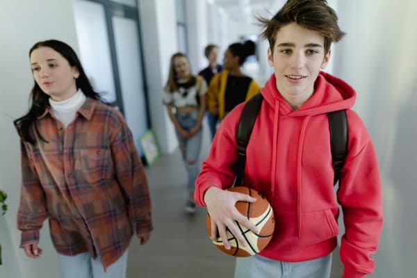 A group of high school students not wearing uniforms walking through the corridors of a hallway.