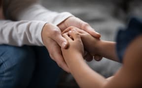 Holding hands of little kid girl, giving psychological help, supporting at home.