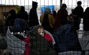 A child waits as people queue inside a migrant registration centre on the Greek island of Samos.