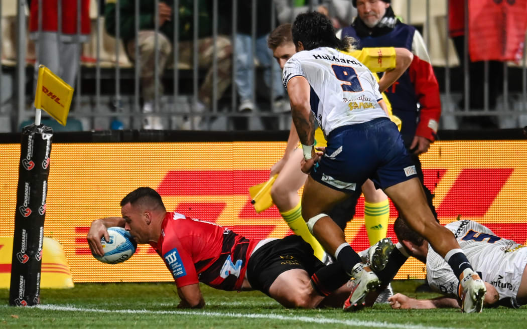 Ryan Crotty of the Crusaders scores a try in the tackle of Allan Craig of Moana Pasifika.