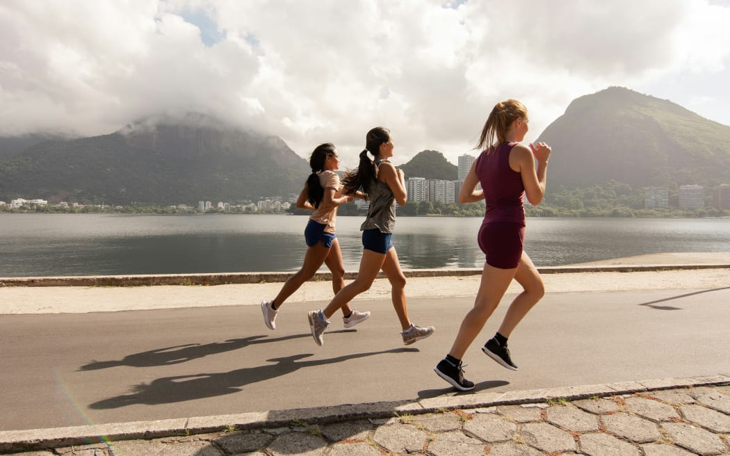 Group running outdoors with mountain and water in the background scenery.