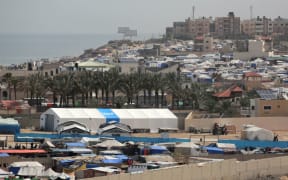 A World Food program (WFP) facility stands amid tents housing internally displaced Palestinians, along the coastline in Deir el-Balah in the central Gaza Strip on May 10, 2024, amid the ongoing conflict between Israel and the militant group Hamas. (Photo by AFP)