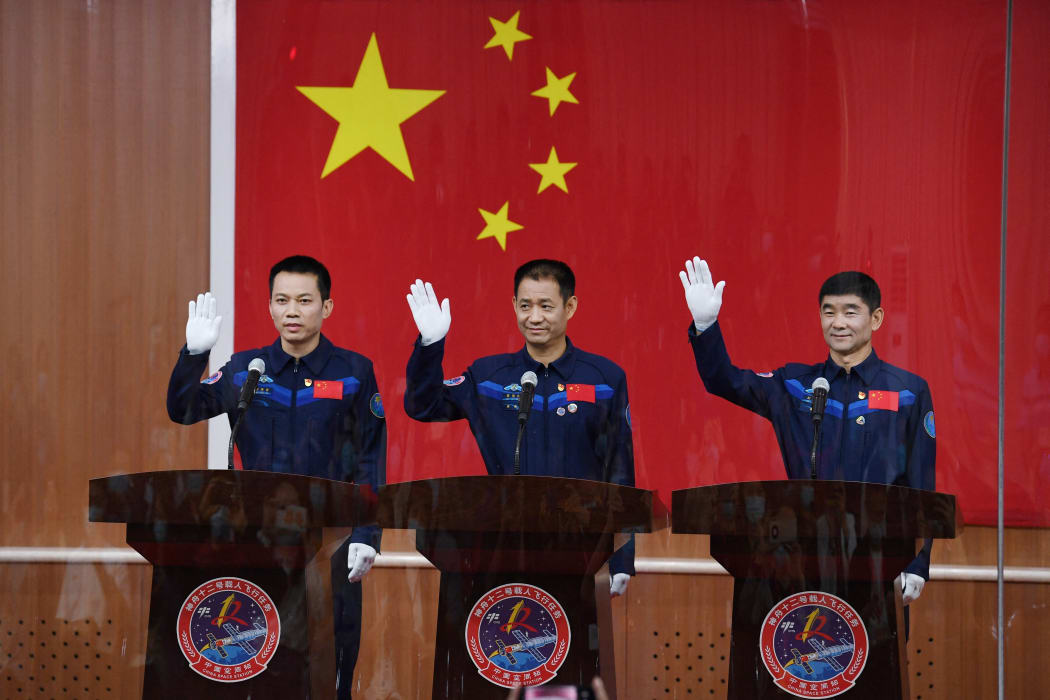 Astronauts Nie Haisheng (centre), Liu Boming (right) and Tang Hongbo wave as they arrive for a briefing the day before their launch in China on 16 June, 2021.