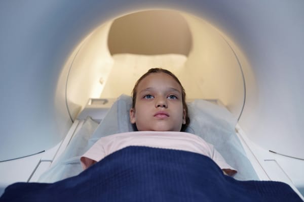 Young girl lying down on a bed and undergoing MRI scan.