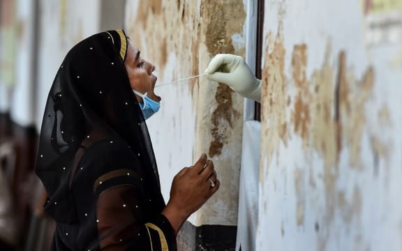 A health official takes a swab sample from a woman to test for the Covid-19 coronavirus at a testing point in Allahabad, India