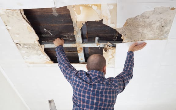 Man repairing collapsed ceiling. Water damaged ceiling from leak.