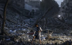 EDITORS NOTE: Graphic content / TOPSHOT - A man walks atop the rubble of a tower destroyed in an Israeli air stike in Gaza City on October 7, 2023. Palestinian militants have begun a "war" against Israel which they infiltrated by air, sea and land from the blockaded Gaza Strip, Israeli officials said, a major escalation in the Israeli-Palestinian conflict. (Photo by MOHAMMED ABED / AFP)