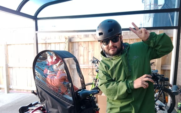 Juan Parada rides in the rain with his five-year-old son.