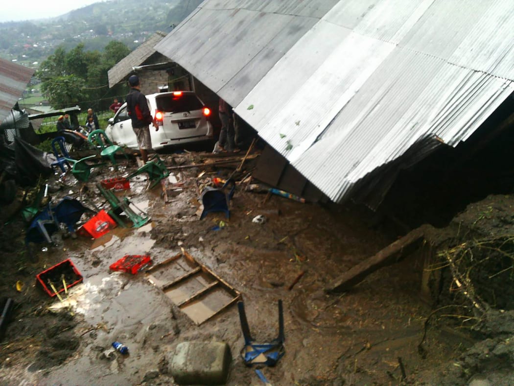Villagers attempt to salvage their belongings from a house damaged in the landslide.