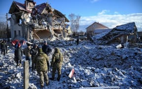 Residents and bomb squad members stand in front of a house destroyed by a Russian missile strike on Saturday.