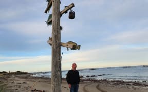 Jeff Burnett with his art piece which helps guide boaties into the bay.