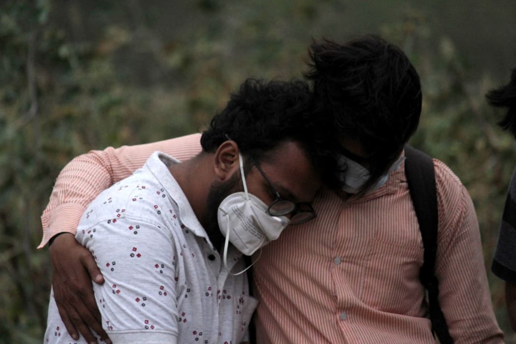 A man is consoled by his relative during the burial of his father, who died of coronavirus (Covid-19), at a graveyard in New Delhi on April 16, 2021.