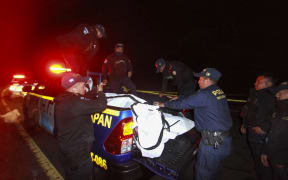 Police officers load the bodies of the victims who died in a road accident onto a truck at Cumbre de Alaska in Totonicapan, Guatemala, on December 27, 2025. At least 15 people died on December 26 when a passenger bus plunged into a ravine on the Inter-American Highway in western Guatemala, rescuers reported. (Photo by Gustavo RODAS / AFP)
