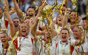 England's flanker Zoe Aldcroft and England's centre Megan Jones lift the winners trophy following the Women’s Rugby World Cup final between Canada and England at Twickenham, 2025.