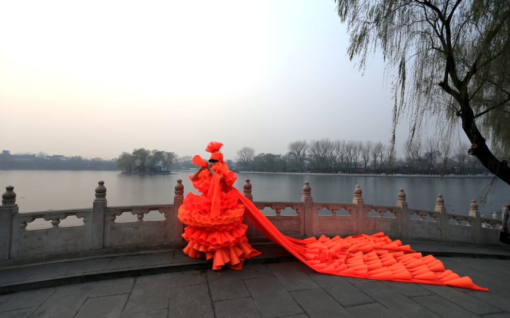 Artist Kong Ning wears an orange face mask and dress to highlight concerns over pollution in China.
