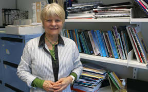 Woman stands in front of  work bookshelf