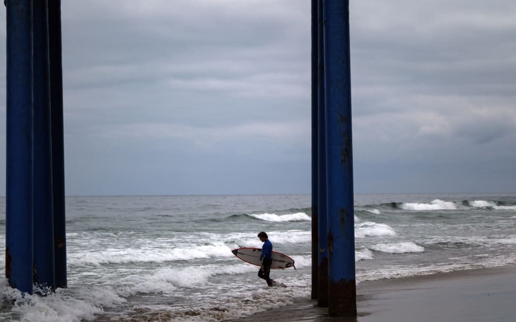 A surfer enters the sea during the Mexican Surf Open Baja California 2023 in Rosarito, Baja California State, Mexico, on 17 September, 2023. (Photo by Guillermo Arias / AFP)