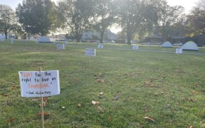 A protest camp in Christchurch's Latimer Square, where signs and tents have been hammered into the grass.