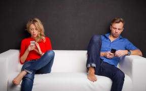 couple on couch each on phones