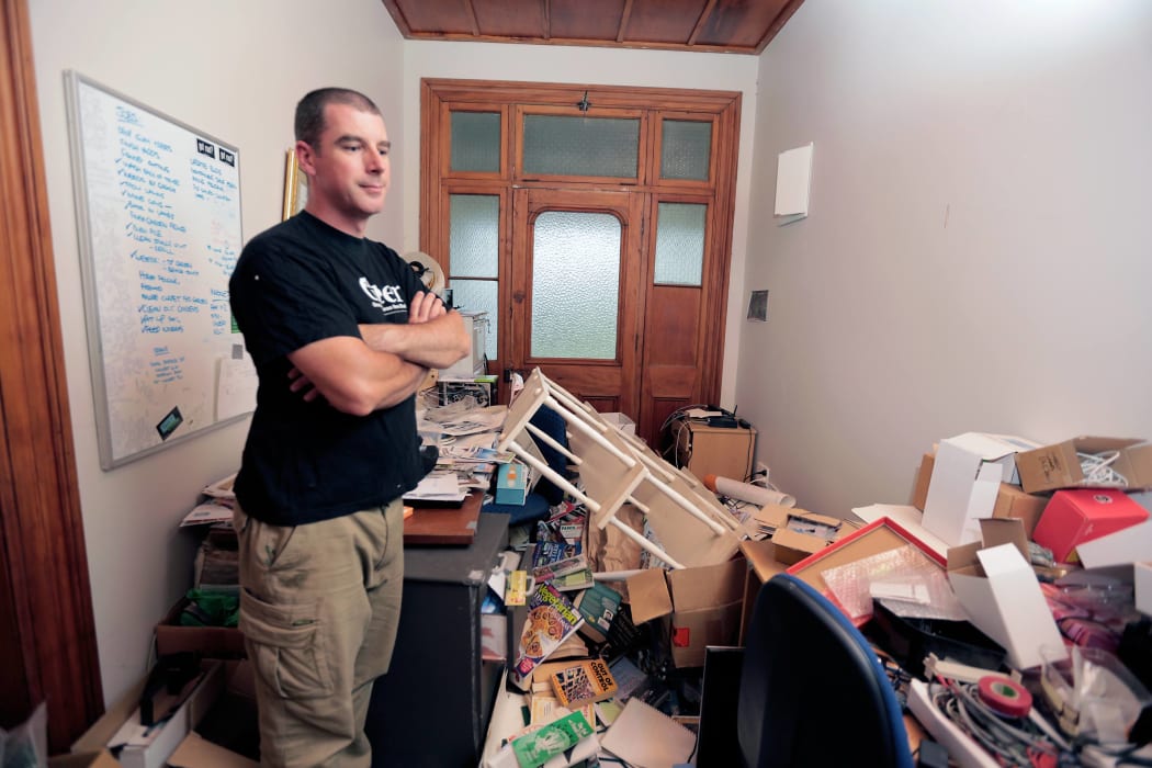 John Hart looking at his home office. All rooms in his house have quake damage