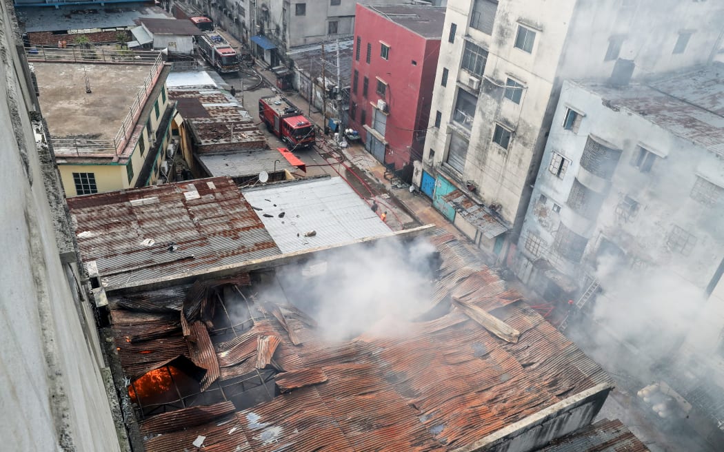 Firefighters douse flames as smoke rises from the burning chemical and garments factory in Dhaka on October 14, 2025. At least 16 people were killed after a fire blazed through a chemical and garments factory in Bangladeshi capital of Dhaka on October 14, fire authorities said. (Photo by AFP)