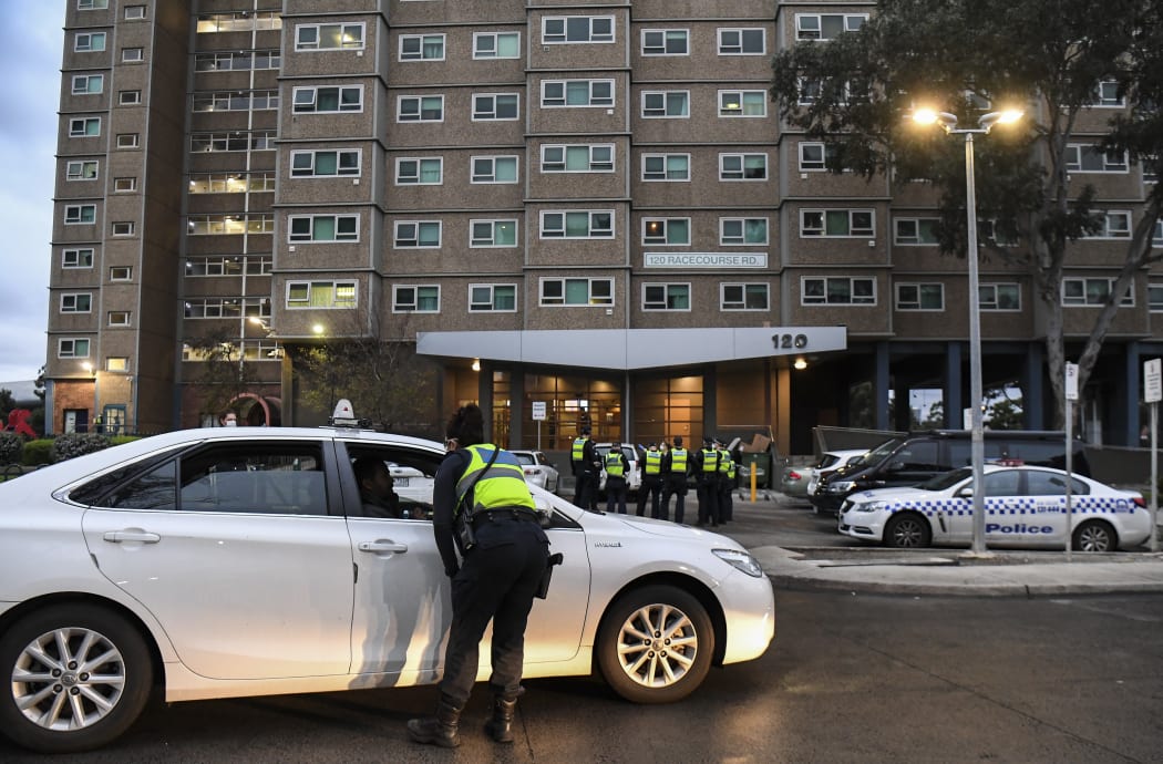 Police gather outside one of nine public housing estates which have been locked down in Melbourne.