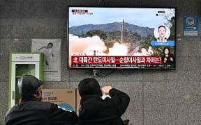 Visitors watch a news broadcast showing file footage of a North Korean missile test at the ferry terminal of South Korea's eastern island of Ulleungdo, in the East Sea, also known as the Sea of Japan, on November 3, 2022. (Photo by Anthony WALLACE / AFP)