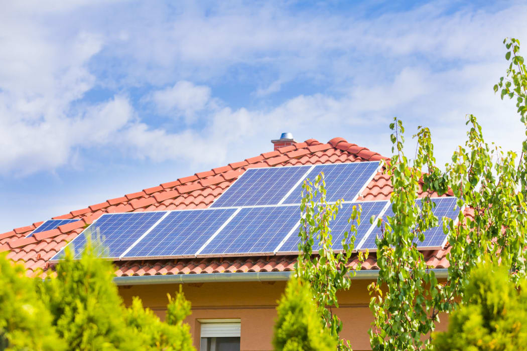 44317184 - solar panel cells on the roof of a new house agains blue sky.