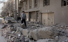 A man makes his way through debris littering a street following airstrikes in central Tehran, on March 4, 2026. Iran's Revolutionary Guards said on March 4, they had total control of the Strait of Hormuz, a key waterway for global energy transit, as Israel launched a new wave of strikes on the Iranian capital. (Photo by AFP)