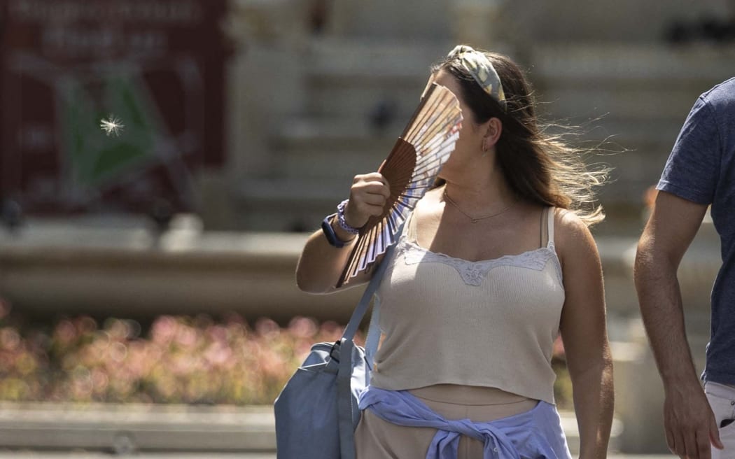 A woman, using a fan, is seen as heatwave hits London.