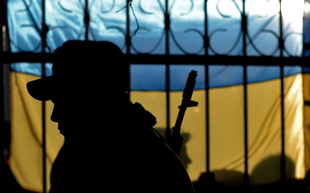 A Ukrainian soldier seen against his country's flag.