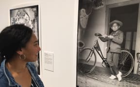 Photographer Edith Amituanai with an image of a Cook Islands boy taken by George Robson Crummer at their exhibition Edith and George: in our sea of Islands.