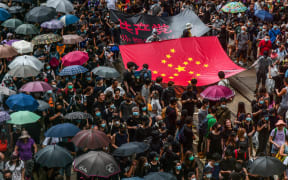 Protesters march with a banner that uses the stars of the Chinese national flag to depict a Nazi Swastika symbol in the Central district of Hong Kong on August 31, 2019.