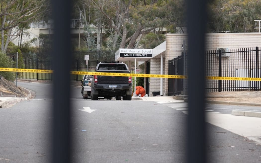 Authorities removing the coloured sand - feared to contain asbestos - from Black Mountain Primary School on Monday.