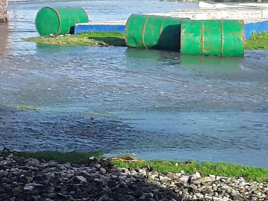 Barrels floating in a flooded area of Aunuu