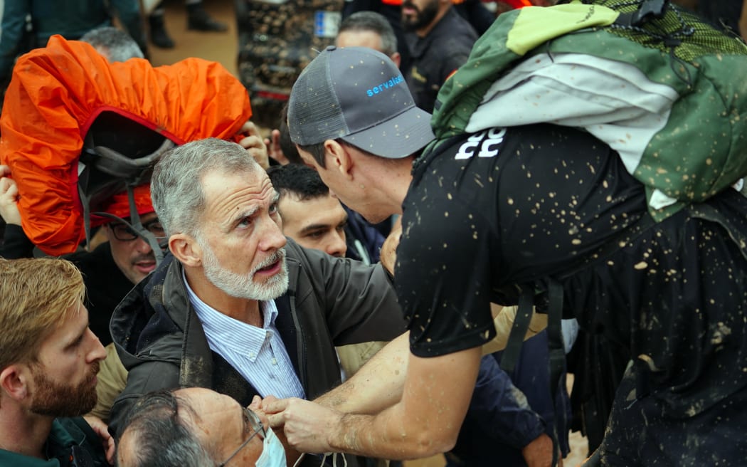 King Felipe VI of Spain (L) talks with a person as angry residents heckle him during his visit to Paiporta, in the region of Valencia, eastern Spain, on November 3, 2024, in the aftermath of devastating deadly floods. - A delegation led by Spain's king and prime minister was heckled today as it visited the Valencia region hit by deadly floods, with some screaming "assassins" and others throwing mud, according to AFP journalists on the scene. King Felipe VI and Queen Letizia visited the town of Paiporta, one of the most affected by the floods that have killed more than 200 people, alongside Prime Minister Pedro Sanchez and other officials. (Photo by Manaure Quintero / AFP)