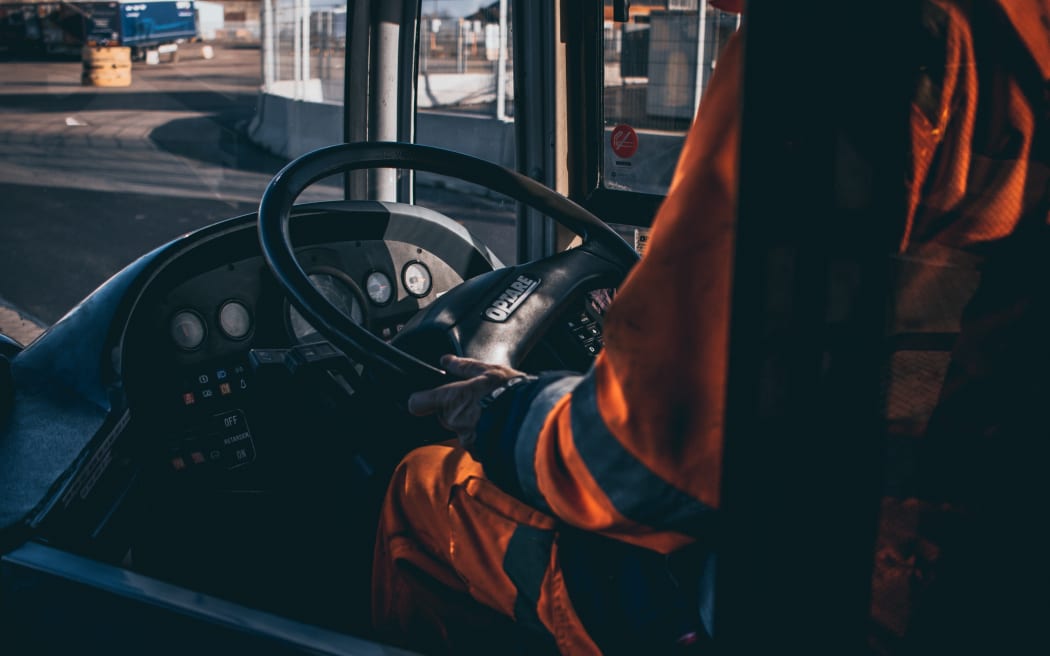 A person sitting in the drivers seat of a bus.