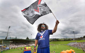 Charlie Raass. NZ Warriors vs Melbourne Storm NRL rugby league trial match at the Rotorua International Stadium.  18 February 2018 Rotorua Daily Post Photograph by Ben Fraser.RGP 23Feb18 - SUPPORTERS: Wayne Temara, Leah Temara, and Dante Temara, 7 are all decked out in their Warriors gear. STAND CHEERS: Thousands of fans take to the stands to cheer on their team. SWISHING: Charlie Raass shows his support with a flag. HUSTLE: Warriors player Lewis Soosemea, right, hustles for the ball.