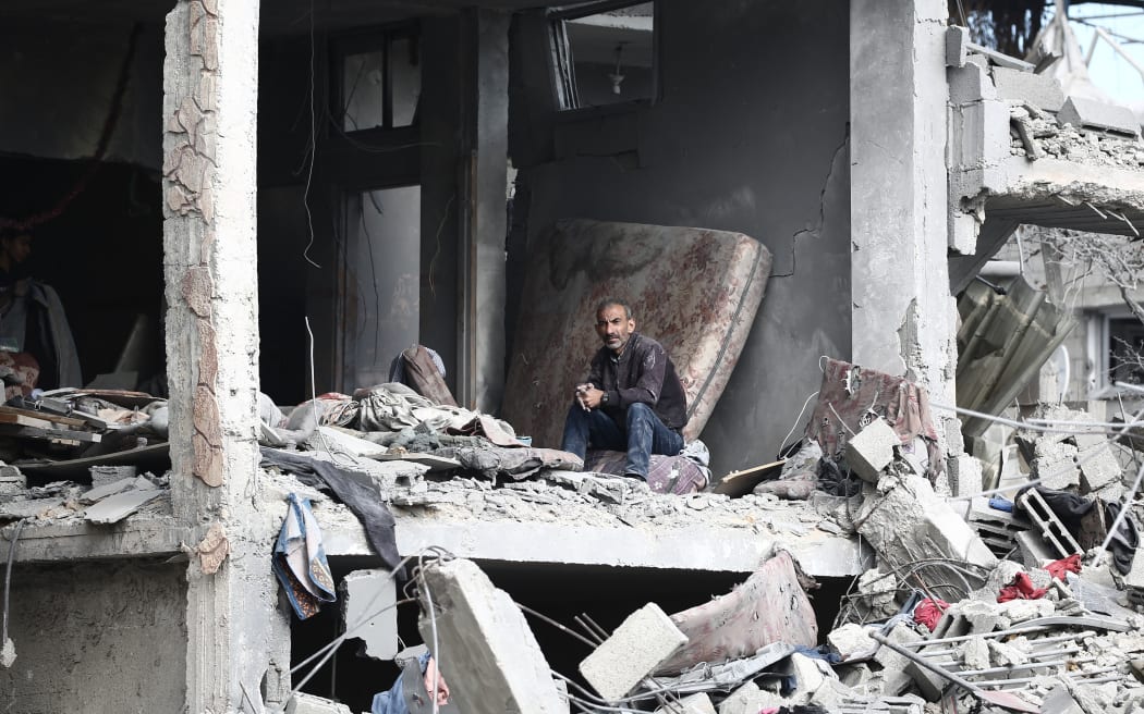 A Palestinian man sits amid the destruction in an apartment building hit in Israeli strikes following his return to Nuseirat in the central Gaza Strip when the bombardment of the camp stopped on November 29, 2024, amid the ongoing war in the Palestinian territory between Israel and Hamas. (Photo by Eyad BABA / AFP)