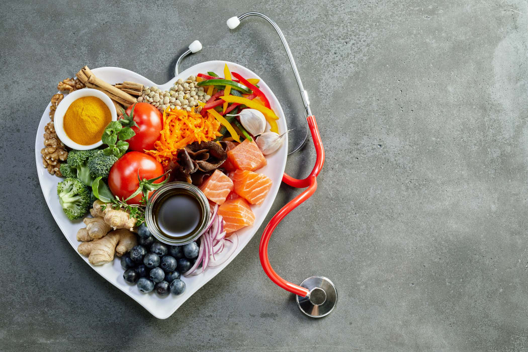 Fresh food for a healthy heart with acai, lentils, soy sauce, ginger, salmon, carrot, tomato, turmeric, cinnamon, walnuts, garlic, peppers, broccoli, basil, onion with a stethoscope and copy space